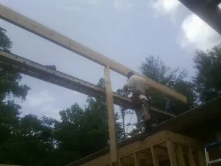 Carpenter setting a ridge beam over a new addition frame — Ice Dam Removal by Roofing Brothers in Barstow