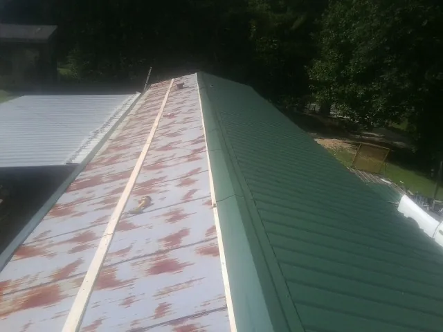 Old rusted panels beside newly installed green metal roofing — Wind Damage Roof Repair by Roofing Brothers in Barstow