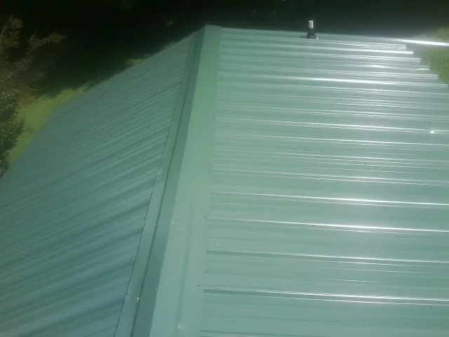 New green metal panels meeting at the ridge of a roof — Flat Roof Repair work by our crew in Barstow