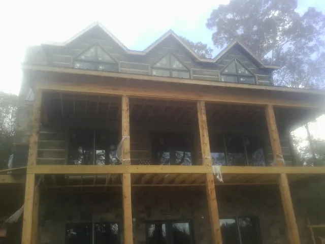 Dormers and porch framing on a large log home under construction — Roof Coating work by our crew in Barstow